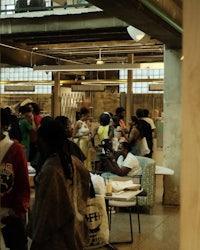 a group of people standing in a room with tables and chairs