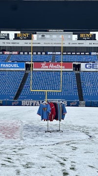 a football field covered in snow with t - shirts on the field