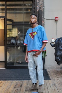 a man in a superman shirt standing in front of a bull